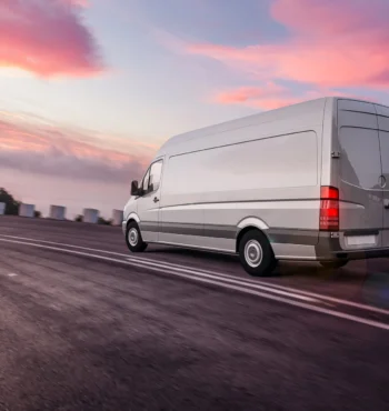 Transporter-Vermietung Grauer Lieferwagen der schnell auf der Autobahn fährt